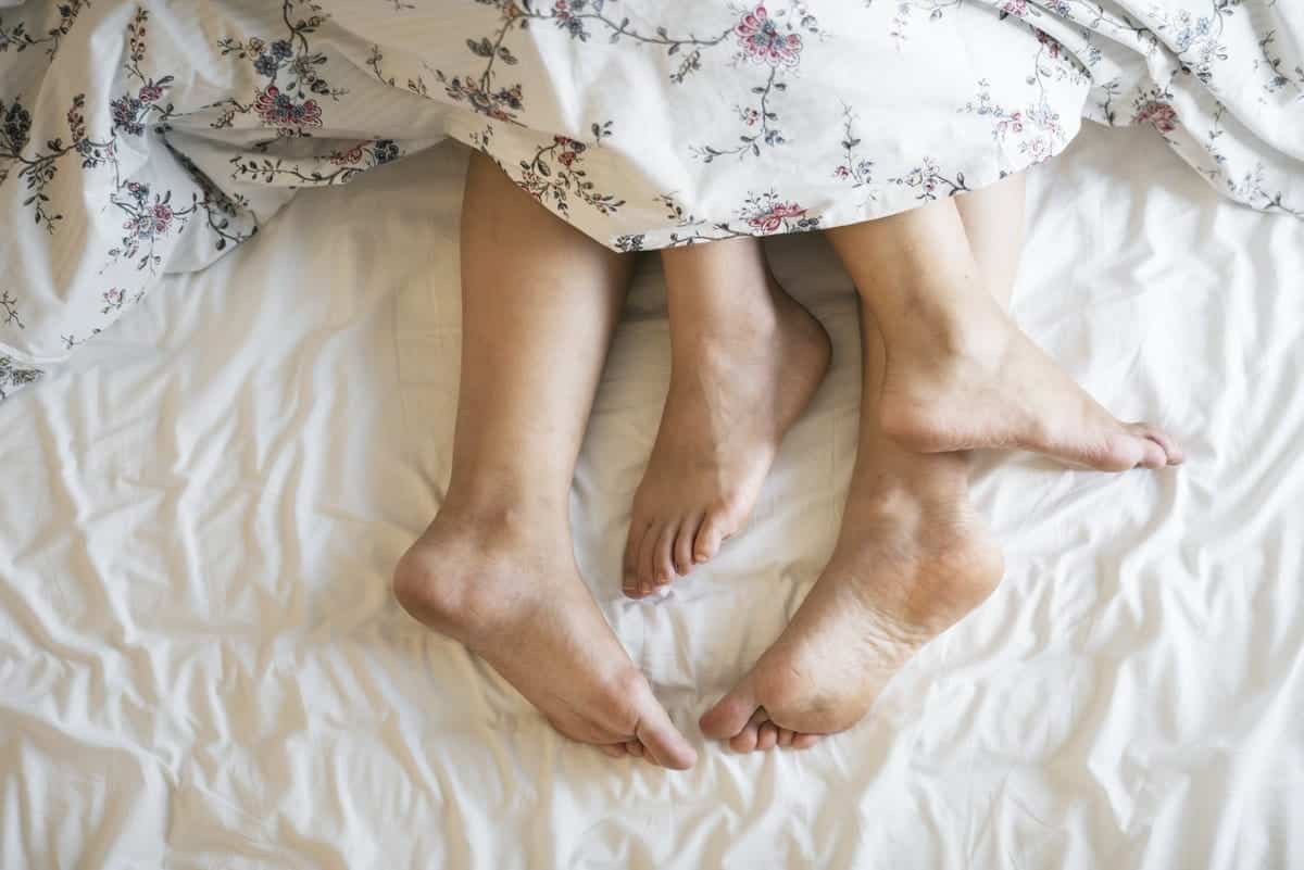 Two People Laying on a Bed Covered With a Floral Comforter