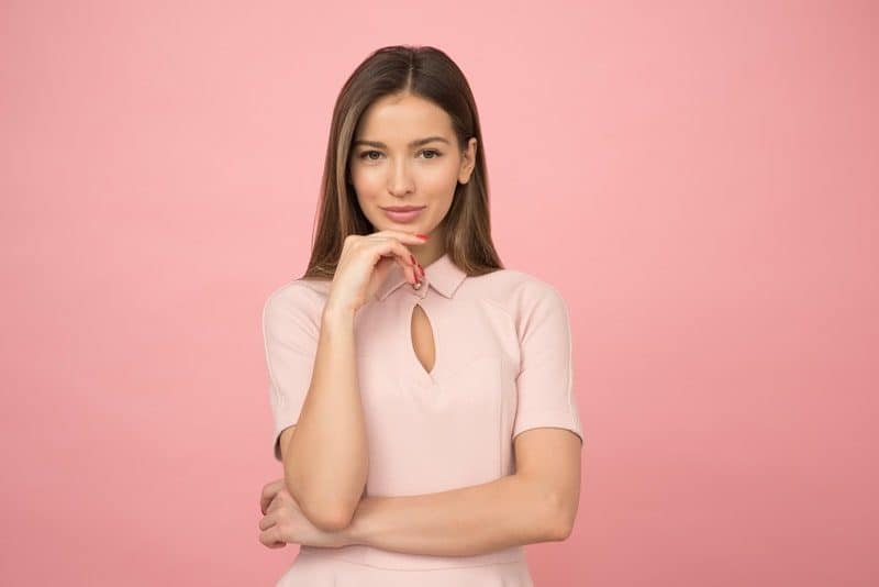 sexy woman smiling in front of a pink background