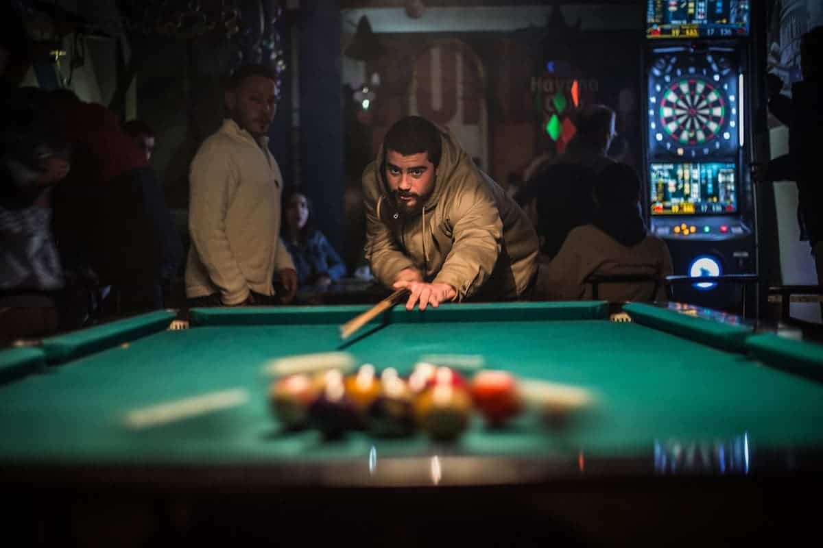 Man Breaking in Pool inside a small bar at night