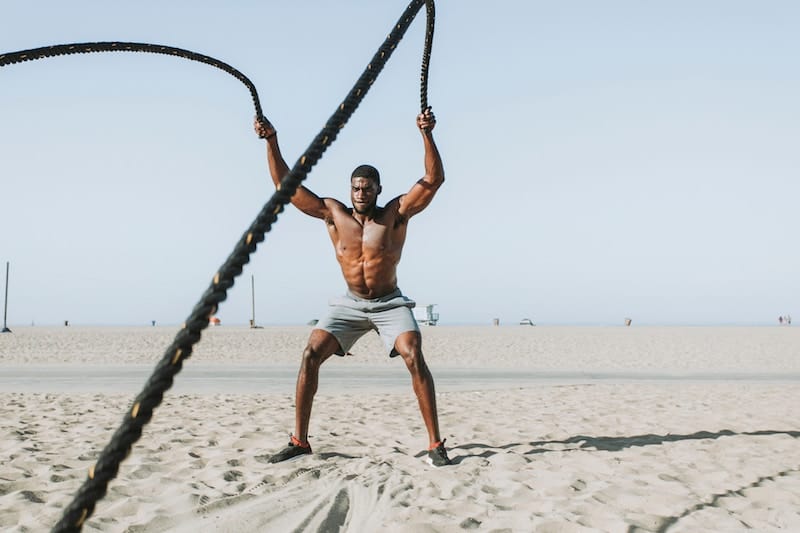 Man doing rope workouts at the beach during noon