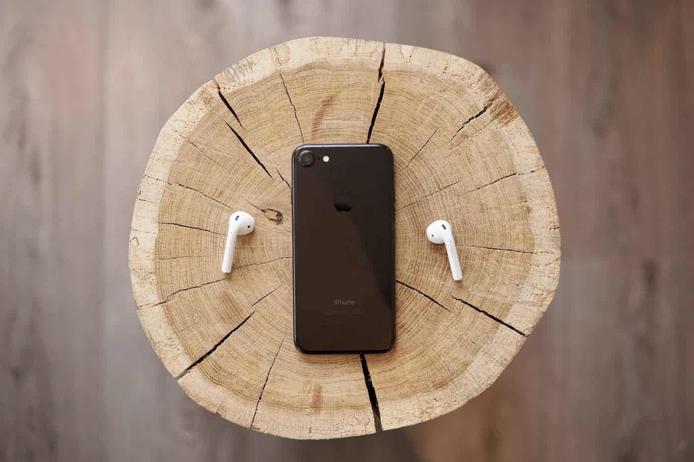 Iphone 7 and apple air pods laying on a wooden chair
