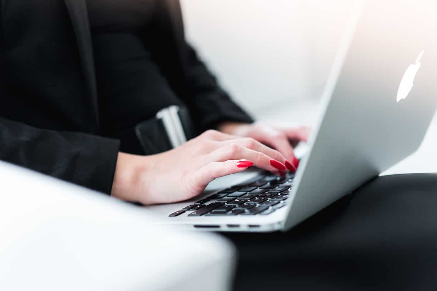 Business Woman With Red Finger Nails Typing on a Macbook Pro