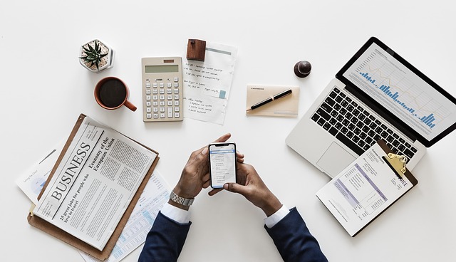 A man looking at his phone, laptop and notebooks.