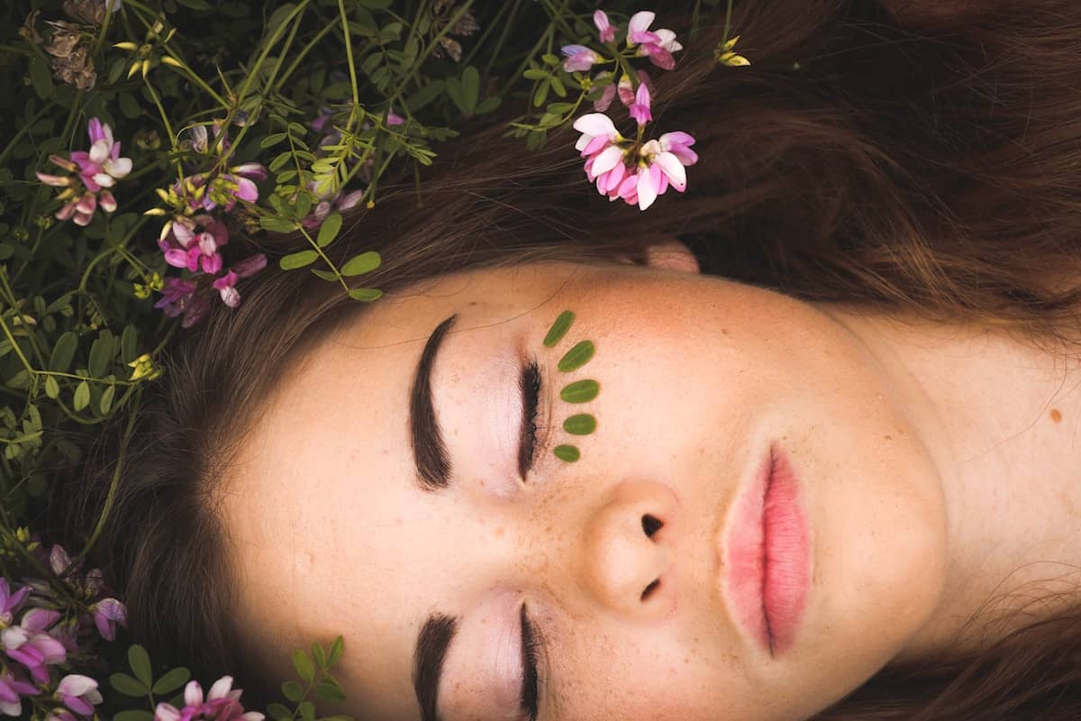 Beautiful Young Woman Laying in a Flower Field