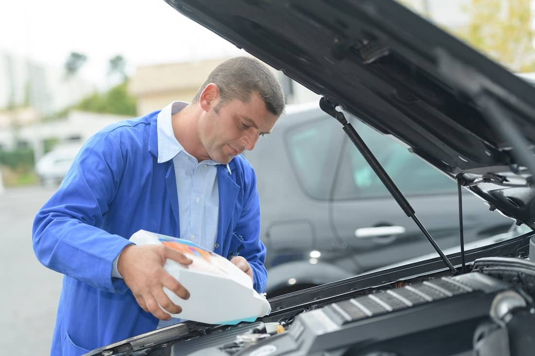 Man refilling vehicle with screen wash