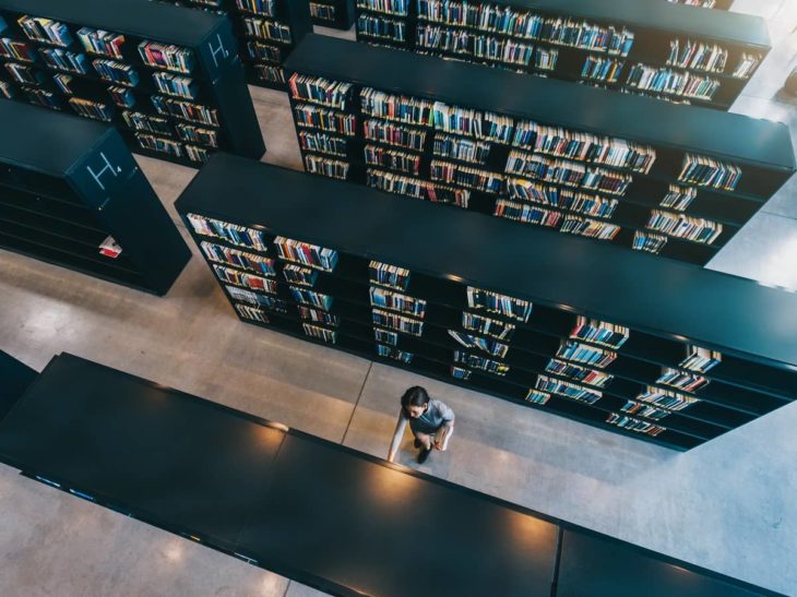 Young woman looking for a book in shelf