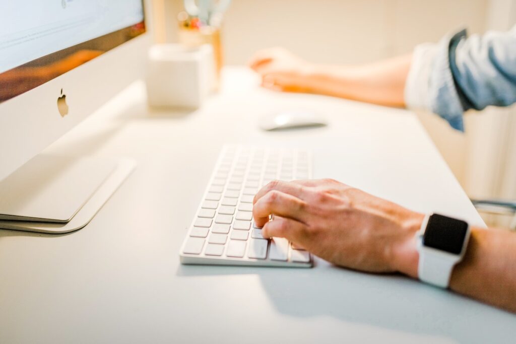 Man Using a White Keyboard on His Desk