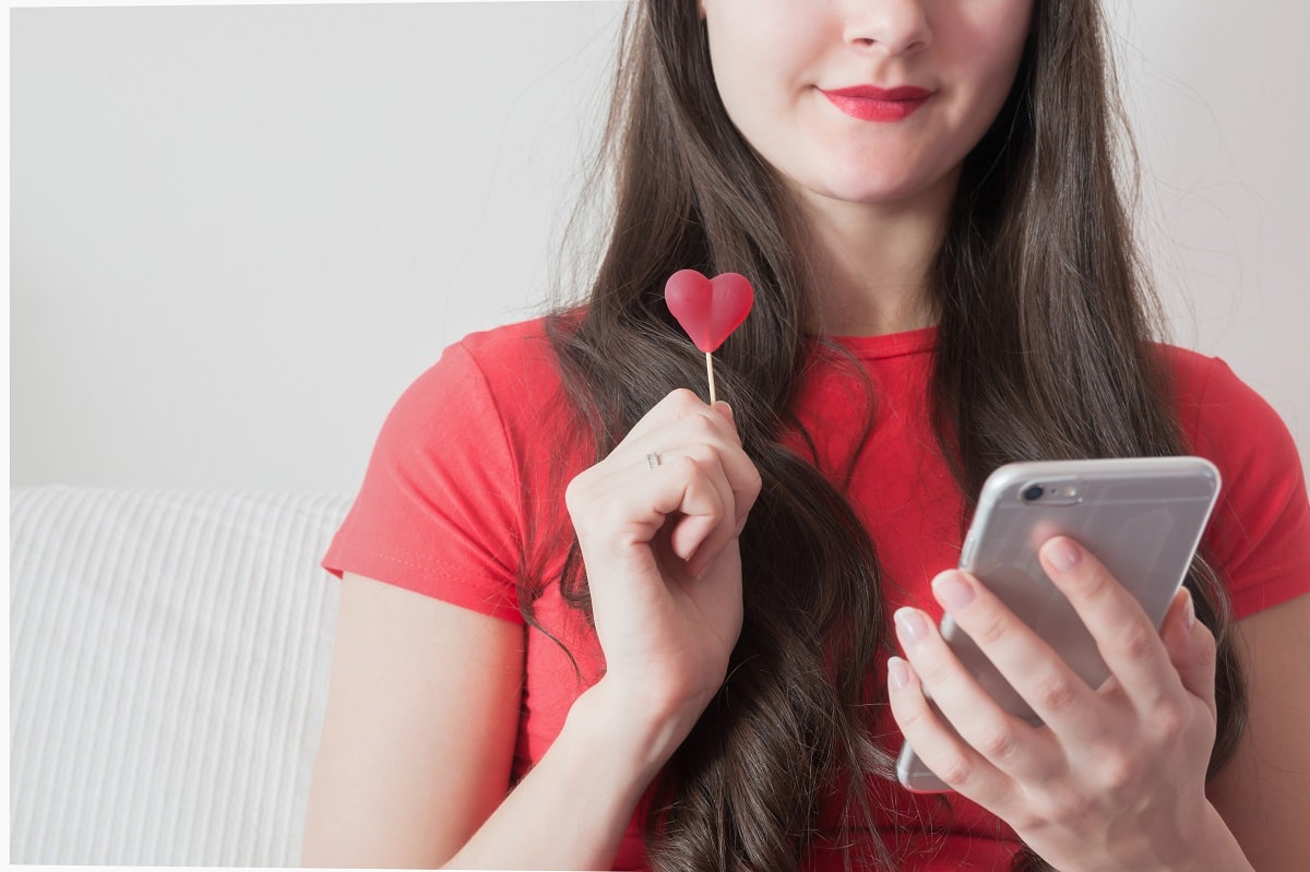Girl with candy heart texting on smart phone