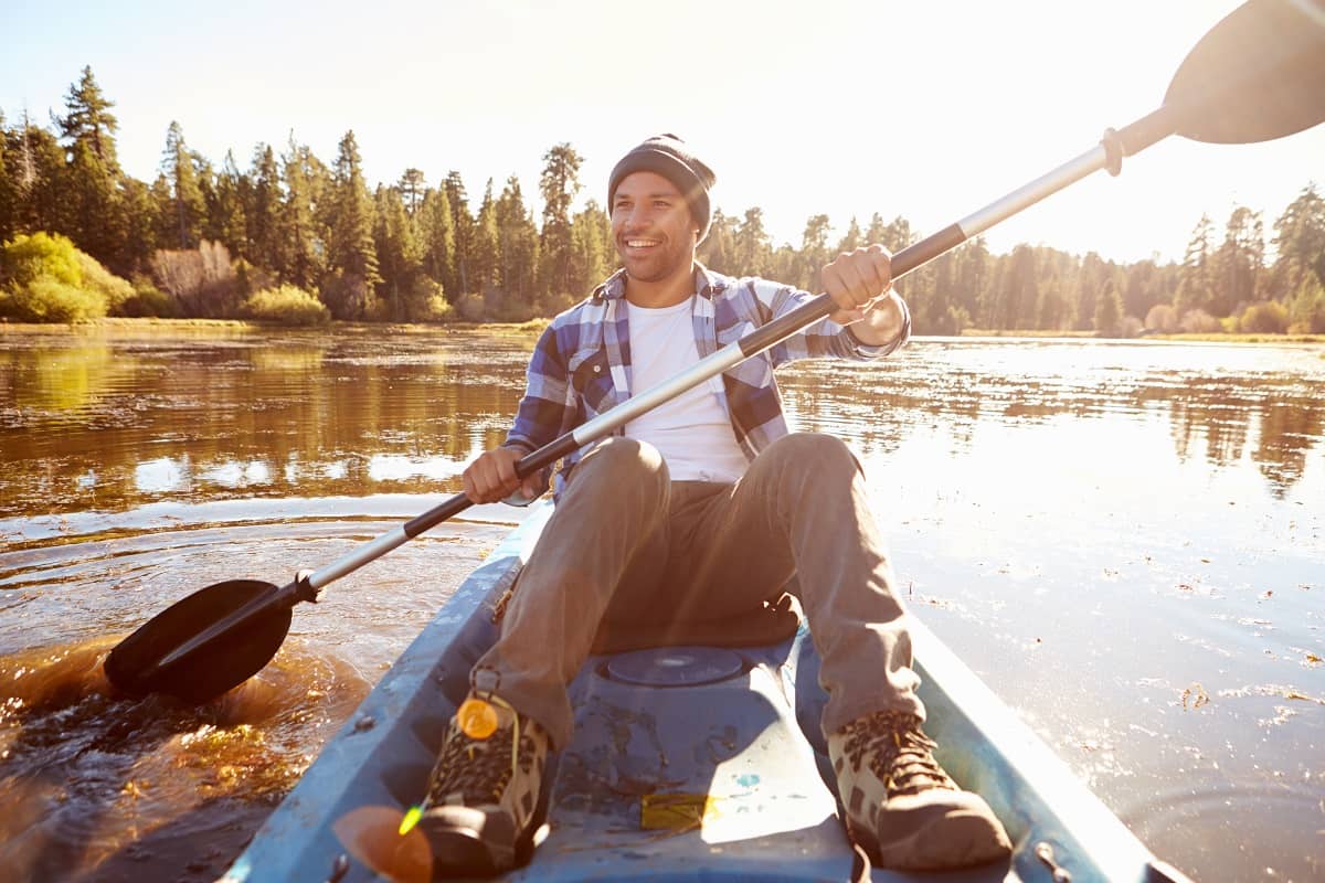 Young Man Rowing Kayak On Lake