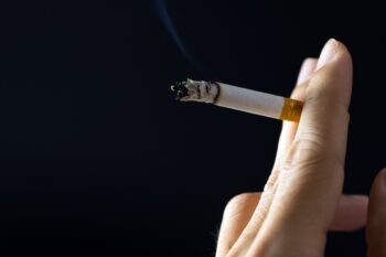 Close up of hand holding cigarette over black background